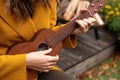girl closeup playing an acoustic instrument ukulele in autumn on the terrace