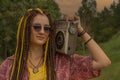 Girl with dreadlocks listens to music on a vintage cassette recorder while sitting in the rays of the setting sun. Royalty Free Stock Photo
