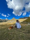 Girl with dreadlocks resting on a hill high in the mountains with her dog Royalty Free Stock Photo