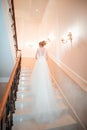 A girl in a dress climbs the stairs. Beautiful lady in a luxurious ball gown climbing the stairs. Baluster railing on both sides.
