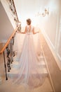 A girl in a dress climbs the stairs. Beautiful lady in a luxurious ball gown climbing the stairs. Baluster railing on both sides.