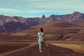 A girl in a dress goes on the road against the backdrop of the mountains of Iceland Royalty Free Stock Photo