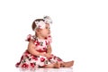 Baby girl in a dress and headband bow sitting barefoot on a white background. Royalty Free Stock Photo