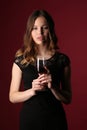 Girl in dress holding glass of wine. Close up. Dark red background Royalty Free Stock Photo