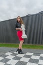 Girl in a dress and leather jacket on the Grand chessboard Royalty Free Stock Photo