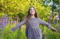 Girl in a dress in a meadow with lupine flowers smiles