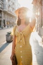 Girl in a dress with a plunging neckline holding a hat on her head on the sunset Royalty Free Stock Photo