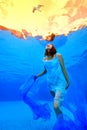 The girl in the dress POPs from the bottom of the pool to the surface and looks at the flying Seagull in the sky. Royalty Free Stock Photo