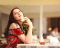 Girl in dress sitting at table in restaurant and enjoy aroma of roses flower waiting a date Royalty Free Stock Photo