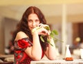 Girl in dress sitting at table in restaurant and enjoy aroma of roses flower waiting a date Royalty Free Stock Photo