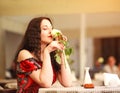 Girl in dress sitting at table in restaurant and enjoy aroma of roses flower waiting a date Royalty Free Stock Photo