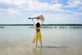 A girl in a dress standing barefoot in the water, holding up a guitar Royalty Free Stock Photo