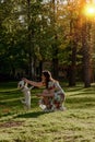 Girl in dress training a dog in park at sunset Royalty Free Stock Photo