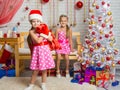 Girl dressed as Santa Claus brought gifts in the bag, another girl rejoices Royalty Free Stock Photo