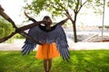 A girl dressed as a witch with an orange skirt and black wings. The girl is seen with her back turned and pruning shears are seen Royalty Free Stock Photo