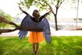 A girl dressed as a witch with an orange skirt and black wings. The girl is seen with her back turned and pruning shears are seen Royalty Free Stock Photo