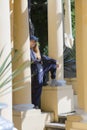 A girl dressed in blue shades in a modern style stands between the columns in the park Royalty Free Stock Photo