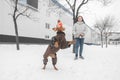 Girl and a dressed dog on a leash play winter in the snow. Photo of a dog jumping over the ball and catching. Woman with a dog Royalty Free Stock Photo