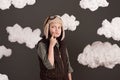 A girl dressed in a retro style jacket and helmet with glasses and dreams of becoming a pilot, clouds of cotton wool, gray