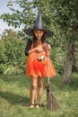 Girl dressed up as a witch with a bucket in the shape of a pumpkin goes on a hunt for sweets on Halloween