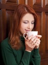 Girl drinking coffee near wood doors. Royalty Free Stock Photo