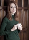 Girl drinking coffee near wood doors. Royalty Free Stock Photo