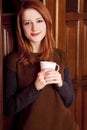 Girl drinking coffee near wood doors. Royalty Free Stock Photo