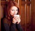 Girl drinking coffee near wood doors. Royalty Free Stock Photo