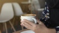 Girl drinking and enjoying coffee during working in cafe. Close-up photo of Asian woman smelling and drinking hot coffee with good