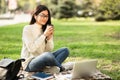 Girl drinking hot coffee, using laptop, sitting in the park Royalty Free Stock Photo