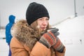 Girl drinking hot tea in the winter forest portrait. A young in warm clothes holding cup with drink on the background of the