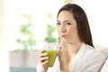 Girl drinking a vegetable green juice looking at you Royalty Free Stock Photo