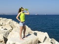 Girl drinking water on large rock by the seaside Royalty Free Stock Photo