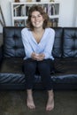 attractive smiling young woman sitting on couch and holding glass of water Royalty Free Stock Photo