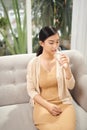 Girl drinking water sitting on a couch at home and looking at camera Royalty Free Stock Photo