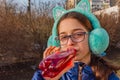 Girl drinks from a bottle in the street. A teenage girl in headphones and glasses