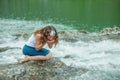 Girl drinks clear water from mountain river