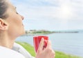 Girl drinks tea on a background sea landscape. Royalty Free Stock Photo