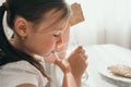 The girl drinks water from a glass glass. A little girl quenches her thirst. Proper nutrition for children. Snack for an