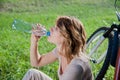 Girl drinks water near the bicycle Royalty Free Stock Photo