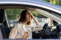 Woman driver being hot during heat wave in car, suffering from hot weather wipes sweat from forehead