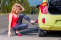 Girl driver tries to replace the punctured wheel Royalty Free Stock Photo