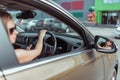 A girl driving a right-hand drive car is parked in a parking lot, near a shopping center, left-hand traffic. Close-up Royalty Free Stock Photo