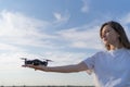 The girl is a drone pilot holding a working drone on her hand at sunset. Working propellers of a small quadcopter in