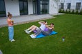 Girl with dumbbells looking at her mom and dad doing crunching on green yard Royalty Free Stock Photo