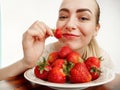 Girl eagerly eating strawberries on white background Royalty Free Stock Photo