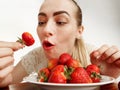 Girl eagerly eating strawberries on white background Royalty Free Stock Photo