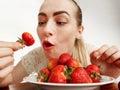 Girl eagerly eating strawberries on white background