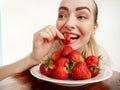 Girl eagerly eating strawberries on white background