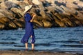 Girl at the eastern beach with long blue dress with feet in the water looking at the relaxed sea, photo taken at Sottomarina Chiog